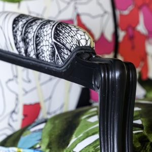 Détail d'une bergère Louis XV rénovée avec des motifs végétaux et floraux.